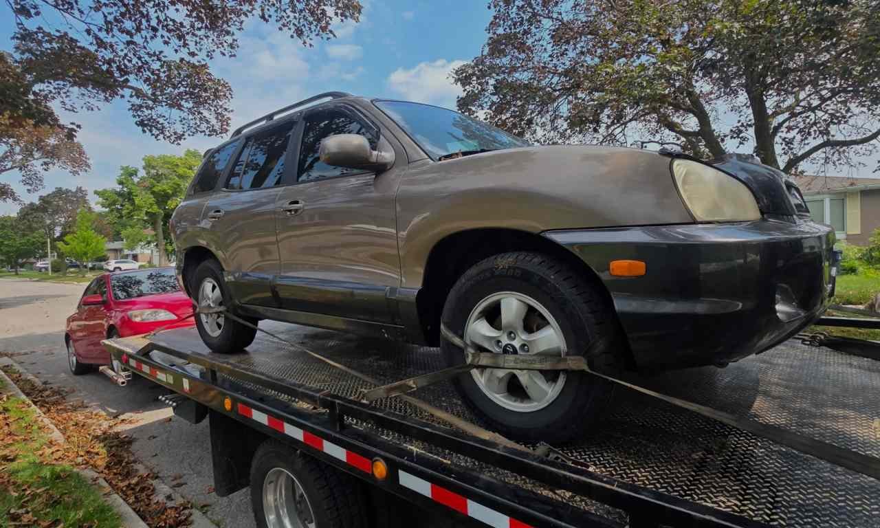 Scrap car secured on flatbed truck for Downtown Toronto removal