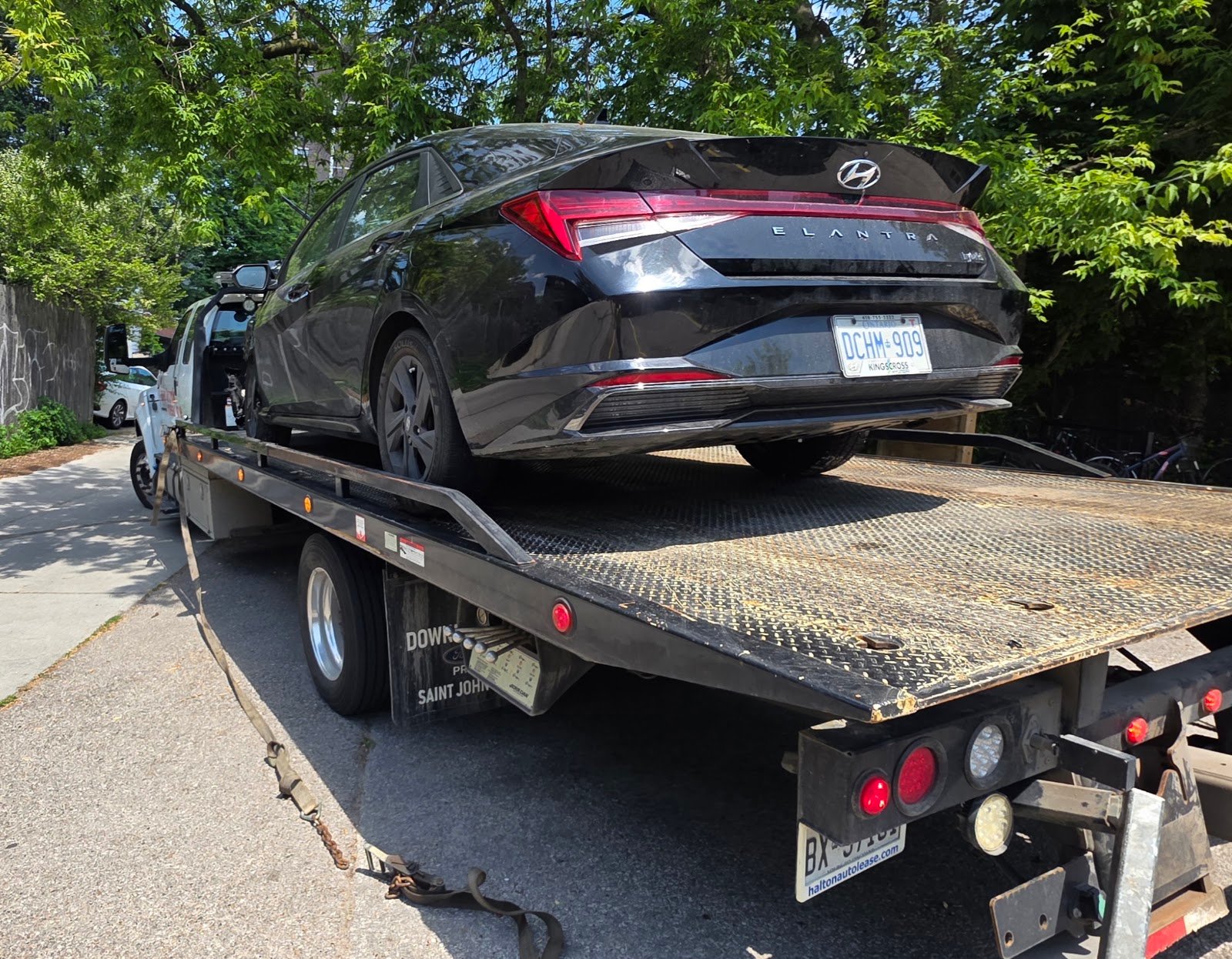 Junk car removal Toronto: flatbed tow truck hauling an old Hyundai