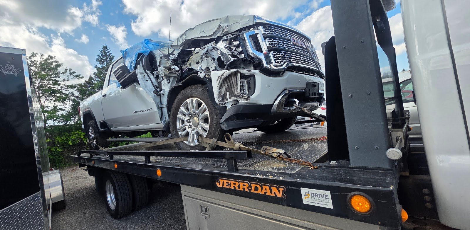 Scrap car towing in Toronto: damaged GMC truck loaded on a flatbed tow truck